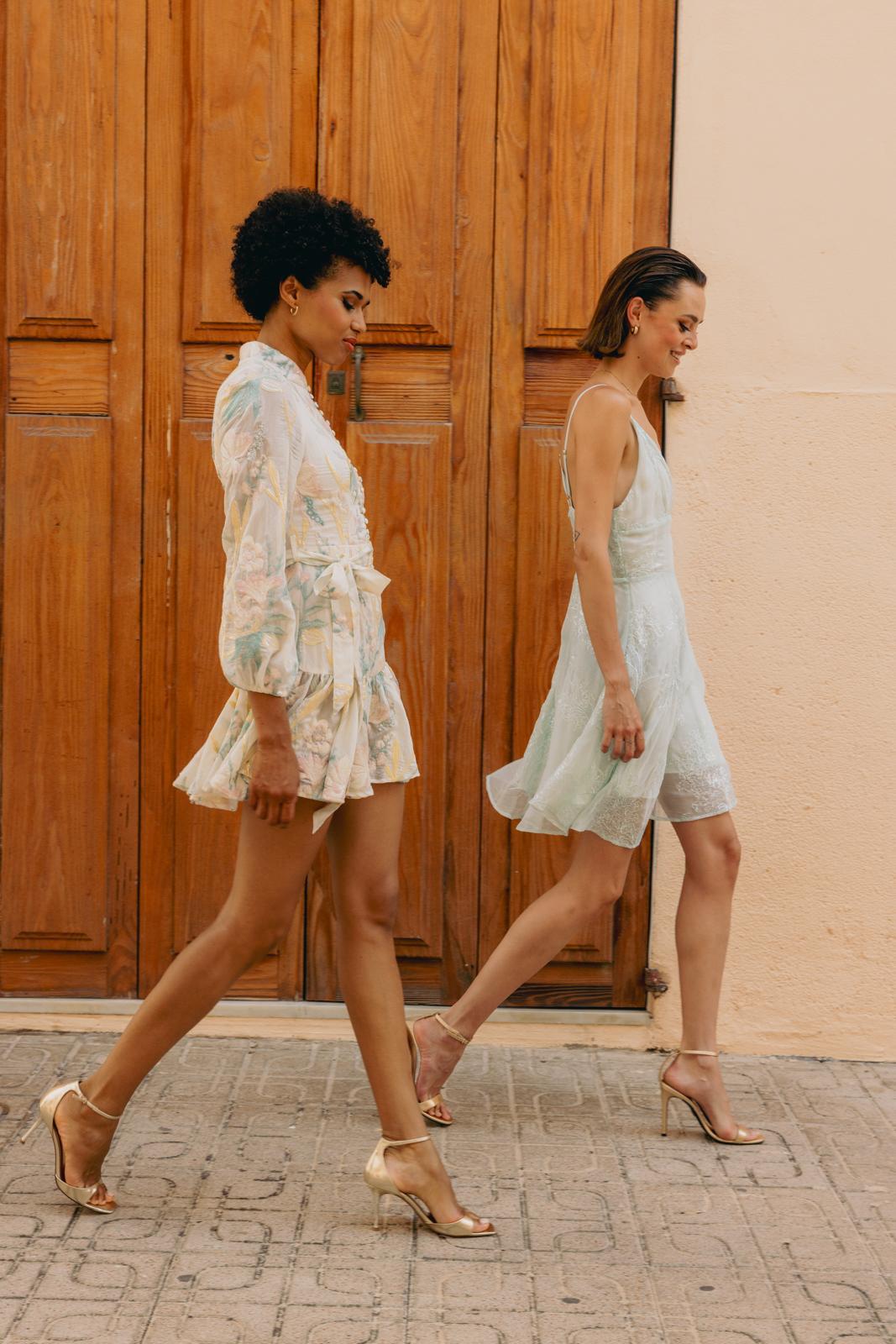 Two DREAMCATCHER dresses passing a wooden door in Ibiza